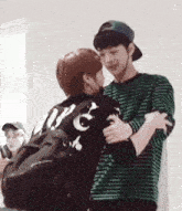 two young men hugging each other in a room .