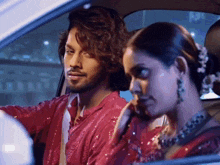 a man and a woman are sitting in a car looking out the window