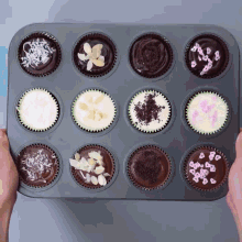 a tray of cupcakes with different toppings and sprinkles on them