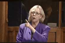 a woman in a purple jacket is pointing
