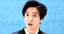 a young man with short hair is making a funny face against a blue background .