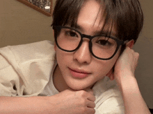 a young man wearing glasses looks at the camera