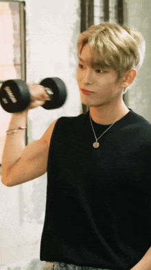 a man in a black tank top is lifting a dumbbell