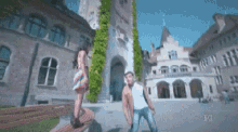 a man and a woman are dancing in front of a building with the letters pg on the bottom
