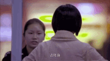 a woman with chinese writing on her back stands in front of another woman