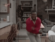 a man wearing a red sweater is dancing in a living room .