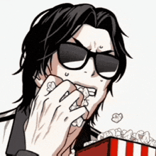 a man wearing sunglasses is eating popcorn from a striped box
