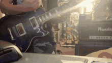 a person is playing a guitar in front of a rando amp