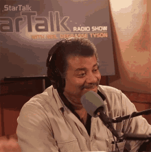 a man wearing headphones and a green microphone is sitting in front of a sign that says startalk radio show