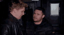 a man in a black leather jacket is standing next to another man in a black jacket