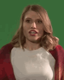 a woman wearing a white shirt and a red scarf is making a funny face on a green screen .