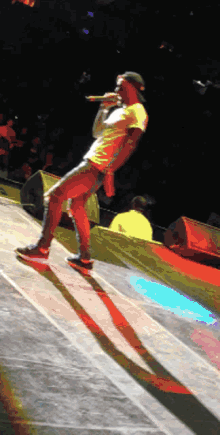 a man in a yellow shirt is singing into a microphone on stage