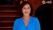 a woman in a blue dress is laughing in front of a tv go logo