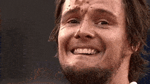 a close up of a man 's face with a beard smiling