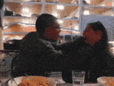 a man and a woman are sitting at a table with a glass of water in front of them