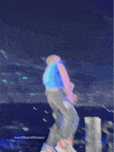 a man in a blue shirt is jumping in the air on a stage with the words swallowedthesea below him