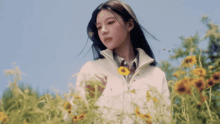 a woman in a white jacket is standing in a field of sunflowers