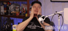 a man is sitting in front of a microphone wearing a black shirt that says dark web