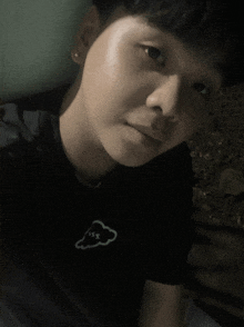 a young man wearing a black shirt with a white cloud on the front