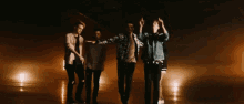 a group of men are dancing in a dark room with their arms in the air