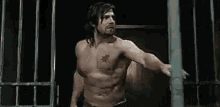 a shirtless man is standing in front of a fence in a dark room .