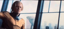 a man in a superhero costume is standing in front of a window in a room .