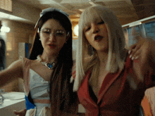 two women standing next to each other with one wearing a red top