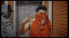 a man covering his face with a red shirt that says 52