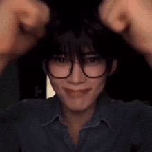 a young man wearing glasses and a blue shirt is making a funny face .