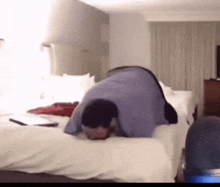 a man in a blue shirt is laying on a bed with his head down