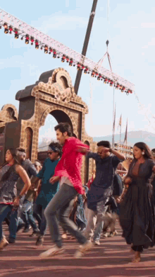 a group of people are dancing in front of a building with a crane in the background