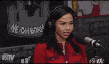 a woman wearing headphones is talking into a microphone in front of a sign that says neighborhoods
