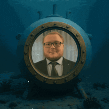a man in a suit and tie is looking out of a window in the ocean