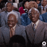 a group of men in suits and ties are sitting in a theatre .