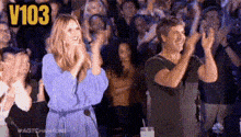 a woman in a blue dress is applauding while a man in a black shirt is clapping .