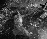 a black and white photo of a man laying on the floor covered in broken glass