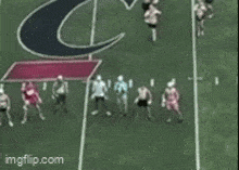 a group of football players on a field with a large c on the sideline