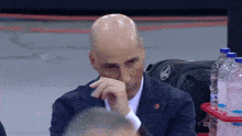 a bald man in a suit with a coca cola logo on his bag