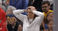a woman holds her head in her hands while watching a game