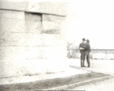 a man in a hat stands in front of a brick wall .