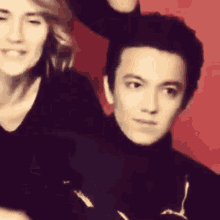 a man and a woman are posing for a photo in front of a red background