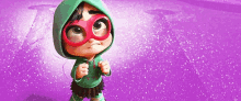 a little girl wearing glasses and a green hoodie stands in front of a purple background