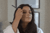 a woman is applying makeup to her eyebrows with a black pencil