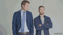 two men standing next to each other with their arms crossed .