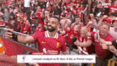 a man in a red jersey is taking a selfie in front of a crowd of people .