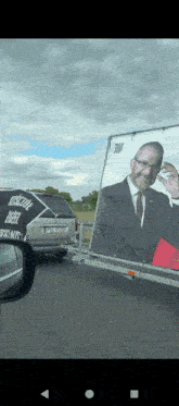 a trailer with a picture of a man on it is being pulled by a white van