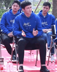 a group of men wearing blue hoodies with chinese writing