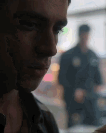 a close up of a man 's face with a blurry background of a police officer