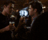 two men are drinking beer in a bar and one of them is holding a glass of beer