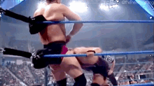 two men are wrestling in a ring with a referee .